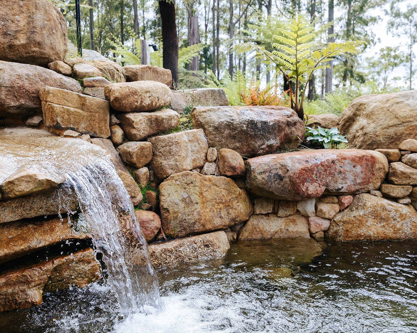 Retaining rock wall with waterfall feature