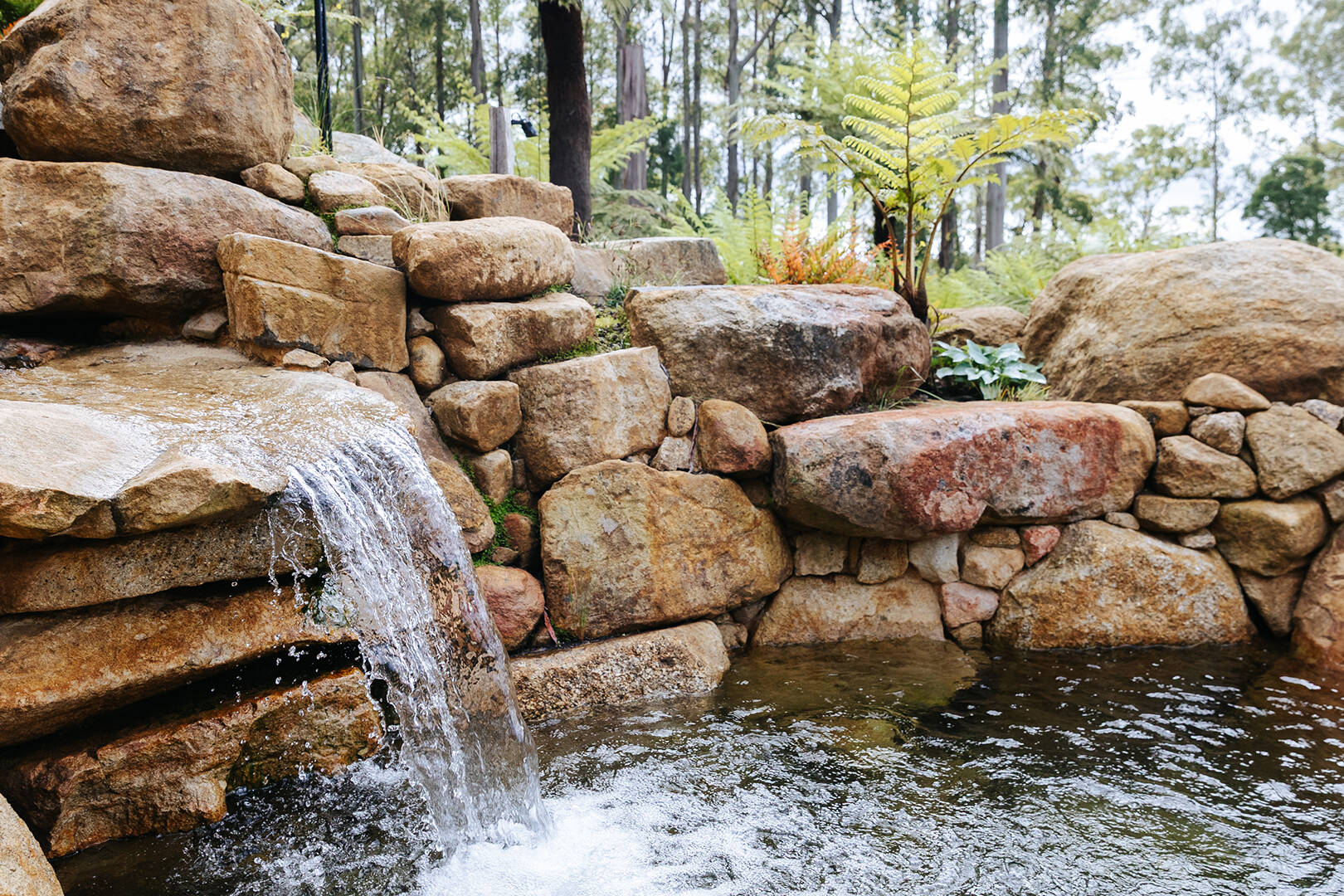 Retaining rock wall with waterfall feature